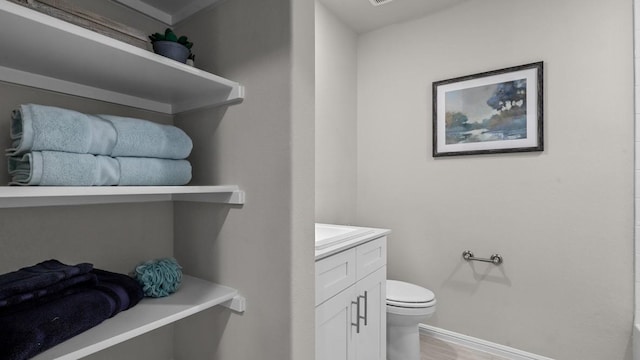 bathroom featuring baseboards, vanity, toilet, and wood finished floors