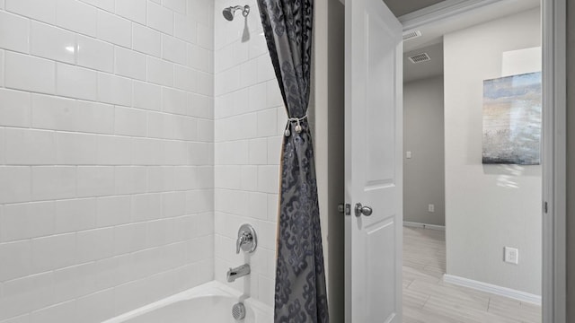 bathroom featuring baseboards, wood finished floors, visible vents, and shower / bathtub combination with curtain