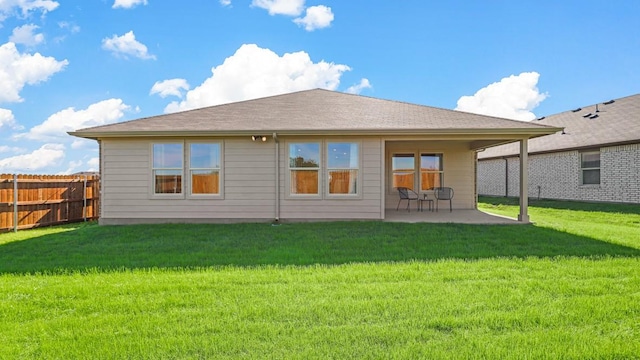 rear view of house featuring a patio area, fence, and a lawn