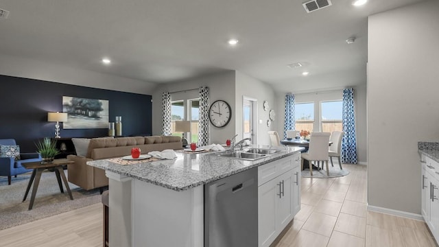 kitchen with a sink, visible vents, white cabinets, dishwasher, and an island with sink