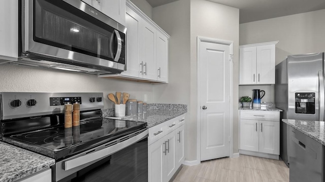 kitchen with appliances with stainless steel finishes, white cabinets, and light stone counters