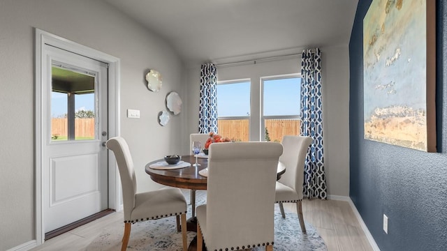 dining area featuring light wood-type flooring, a wealth of natural light, and baseboards