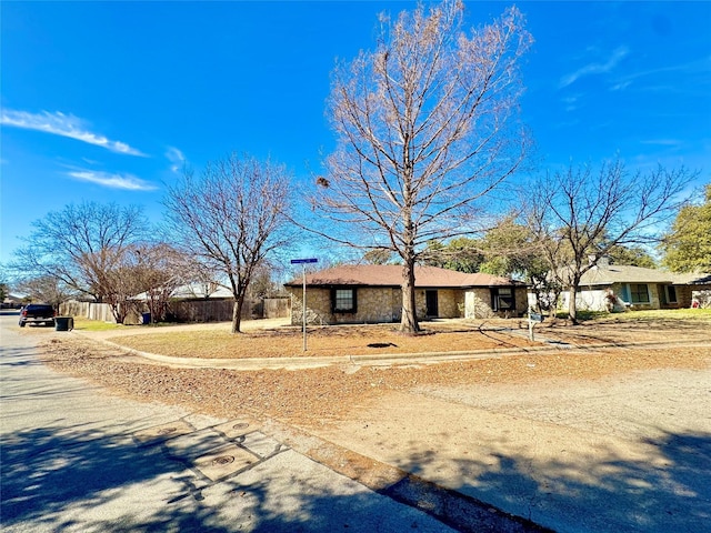 single story home with stone siding and fence