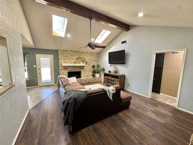 living area featuring lofted ceiling with skylight, a brick fireplace, a textured wall, and wood finished floors