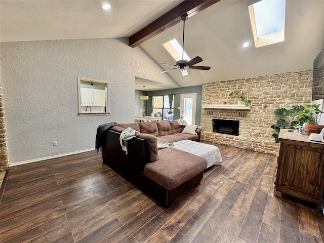 living room featuring a skylight, beam ceiling, a fireplace, dark wood finished floors, and a textured wall