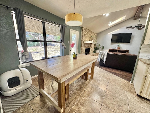 dining space featuring lofted ceiling, light tile patterned floors, ceiling fan, and a fireplace