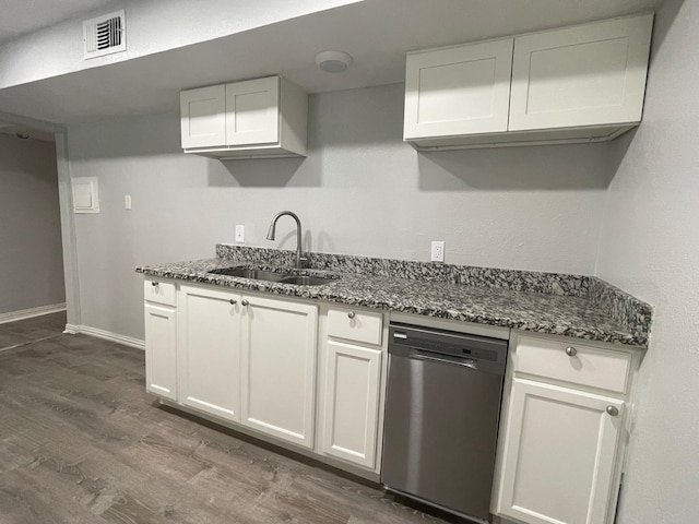 kitchen featuring visible vents, stainless steel dishwasher, white cabinets, a sink, and dark stone counters