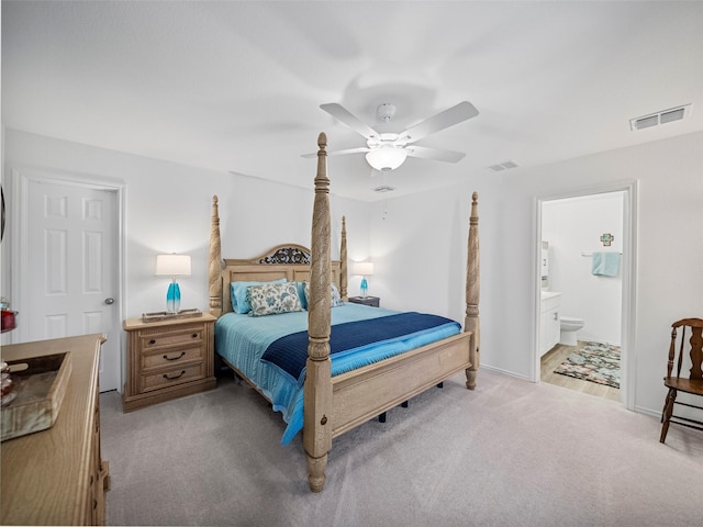 bedroom with light carpet, ceiling fan, visible vents, and ensuite bathroom