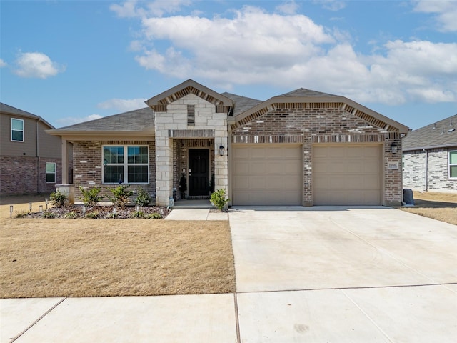 view of front of home featuring brick siding, an attached garage, stone siding, driveway, and a front lawn