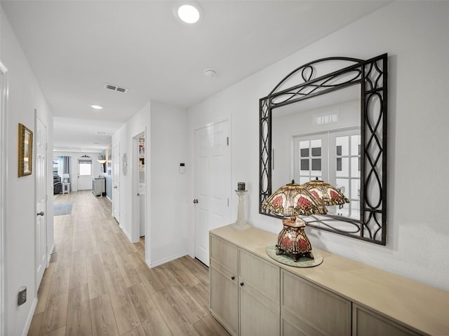 hall featuring light wood-type flooring, baseboards, visible vents, and french doors