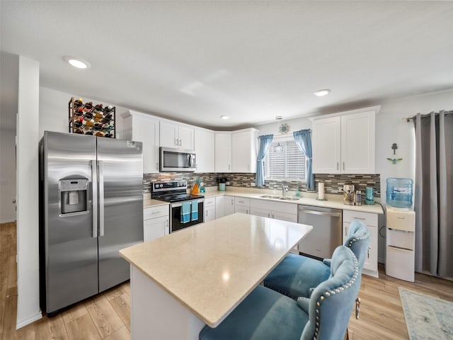 kitchen with a center island, light countertops, appliances with stainless steel finishes, white cabinetry, and a sink