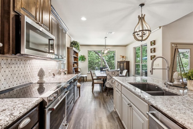 kitchen featuring dark brown cabinetry, light stone counters, dark wood-type flooring, stainless steel appliances, and a sink