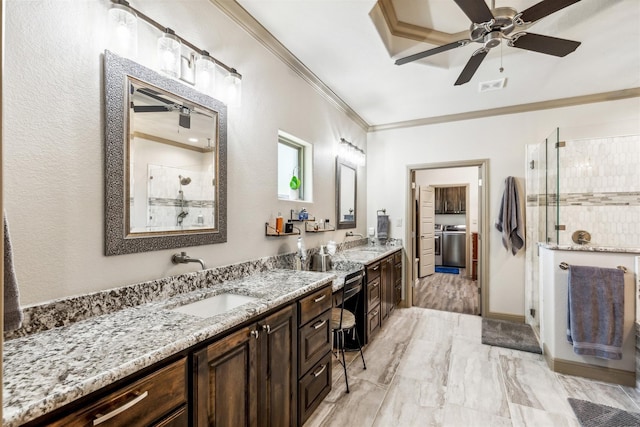 bathroom with ornamental molding, washer and clothes dryer, a sink, and a shower stall