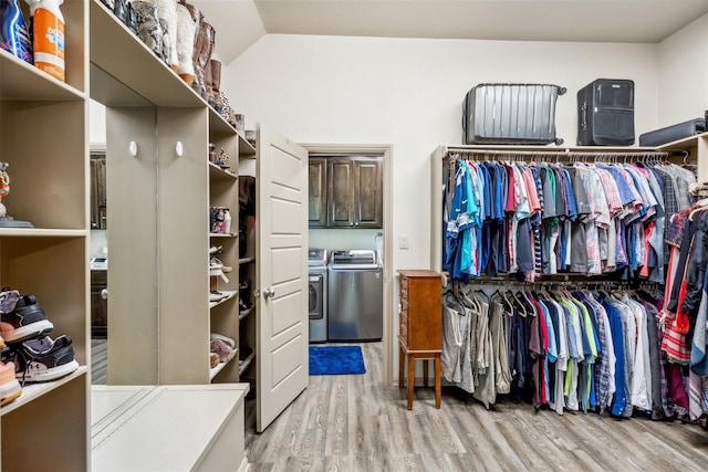 walk in closet with light wood finished floors, vaulted ceiling, and independent washer and dryer