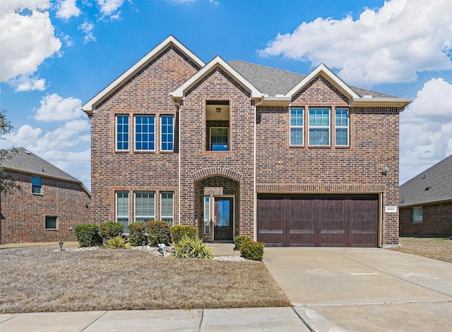 traditional-style home featuring a shingled roof, concrete driveway, brick siding, and an attached garage