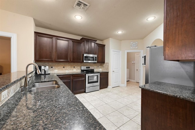 2601 Sabine Cir, Royse City, TX 75189 - kitchen with appliances with stainless steel finishes, a sink, tasteful backsplash, dark brown cabinetry, and dark stone countertops