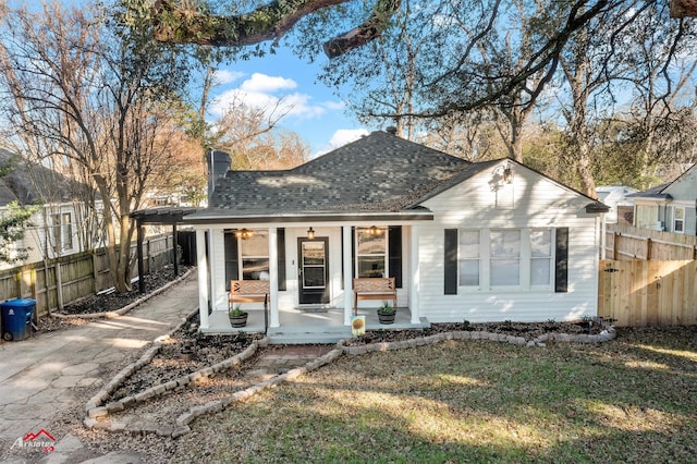 view of front of home featuring a chimney, a porch, a shingled roof, a front yard, and fence