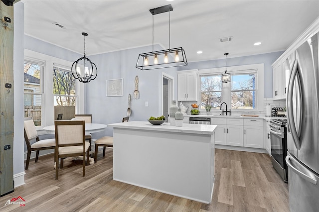 kitchen featuring white cabinets, appliances with stainless steel finishes, light countertops, and decorative light fixtures