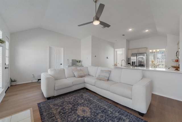 living area with lofted ceiling, wood finished floors, a ceiling fan, and baseboards