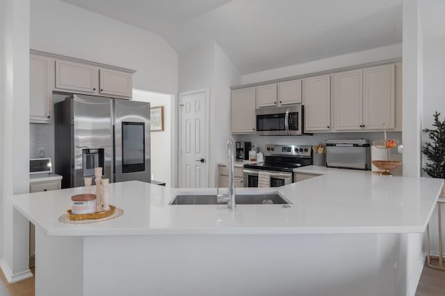 kitchen featuring gray cabinets, vaulted ceiling, appliances with stainless steel finishes, and light countertops