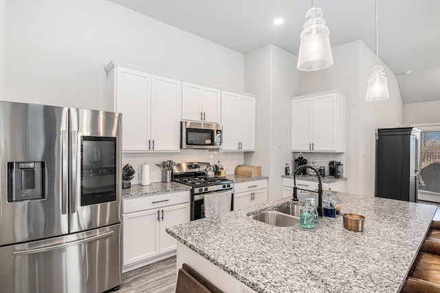 kitchen with appliances with stainless steel finishes, pendant lighting, white cabinetry, and a sink