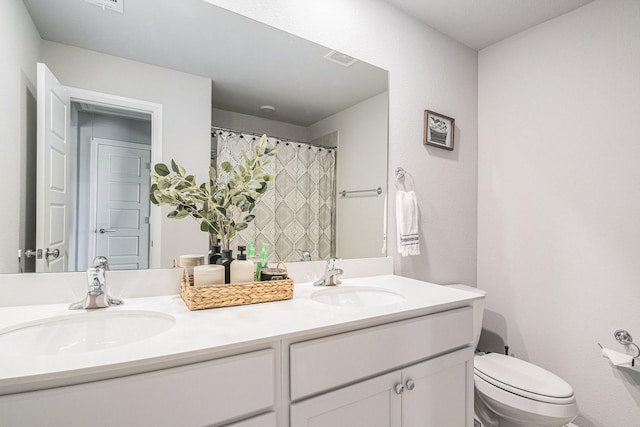 full bathroom featuring visible vents, double vanity, a sink, and toilet