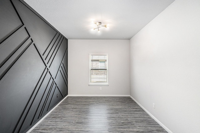 unfurnished room featuring dark wood-style floors, baseboards, and a textured ceiling