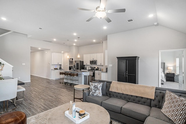 living area featuring a ceiling fan, visible vents, baseboards, and wood finished floors