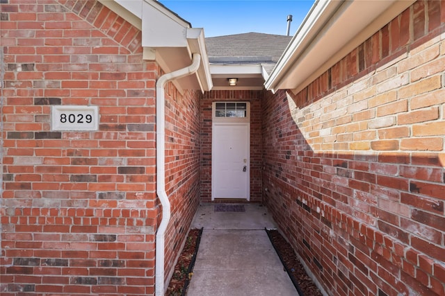 entrance to property with brick siding and roof with shingles