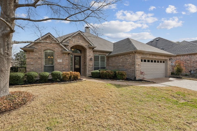 view of front facade featuring brick siding, a shingled roof, driveway, a chimney, and a front yard