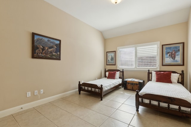 bedroom with lofted ceiling, light tile patterned floors, and baseboards