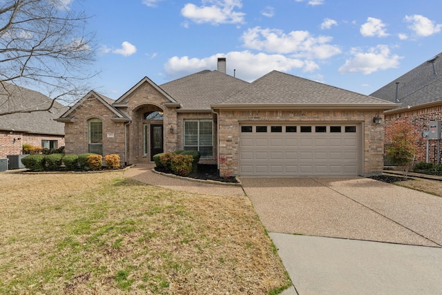 view of front of house with brick siding, a chimney, a shingled roof, cooling unit, and driveway