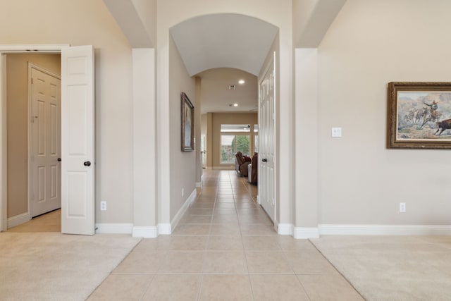 hallway featuring light carpet, light tile patterned floors, and baseboards