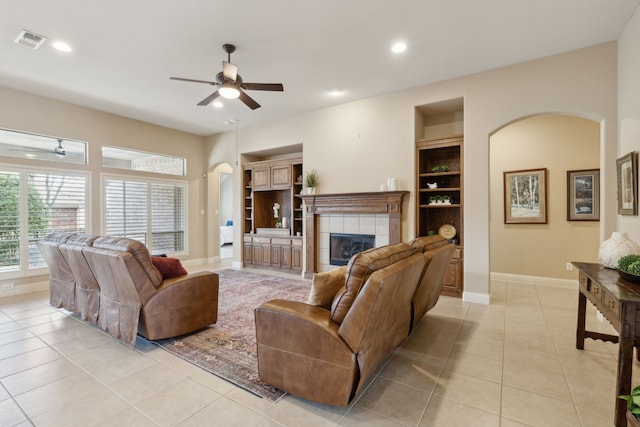 living room featuring a ceiling fan, arched walkways, visible vents, and light tile patterned floors