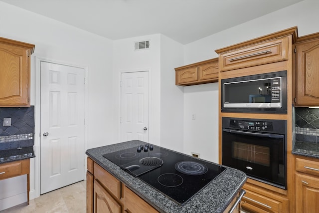 kitchen with dark stone counters, tasteful backsplash, black appliances, and a center island