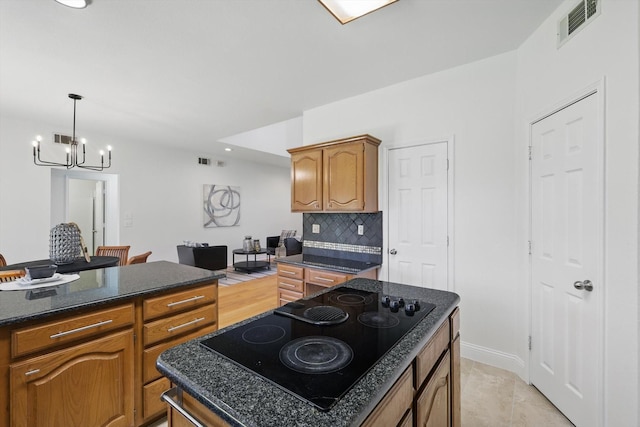 kitchen with black electric stovetop, visible vents, backsplash, and a kitchen island