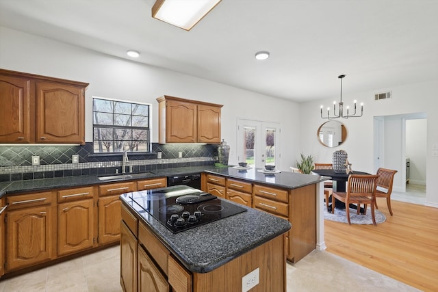 kitchen featuring visible vents, a kitchen island, a peninsula, black appliances, and a sink