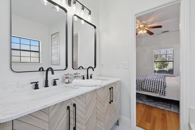 bathroom with double vanity, connected bathroom, visible vents, and a sink