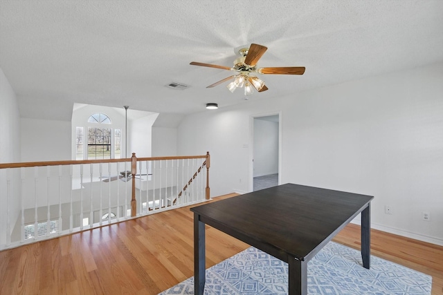 unfurnished office with visible vents, a textured ceiling, a ceiling fan, and wood finished floors