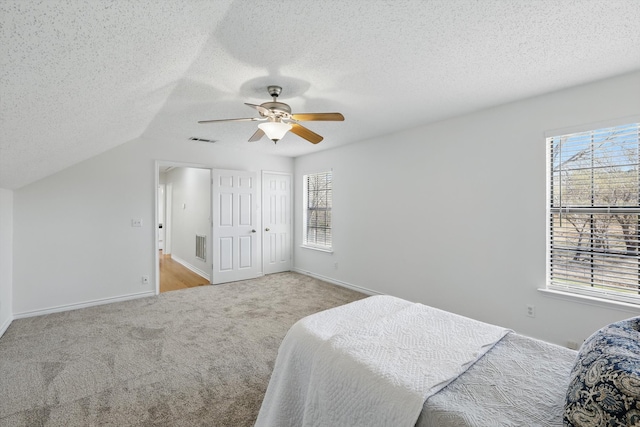 bedroom featuring visible vents, carpet floors, a textured ceiling, and a ceiling fan