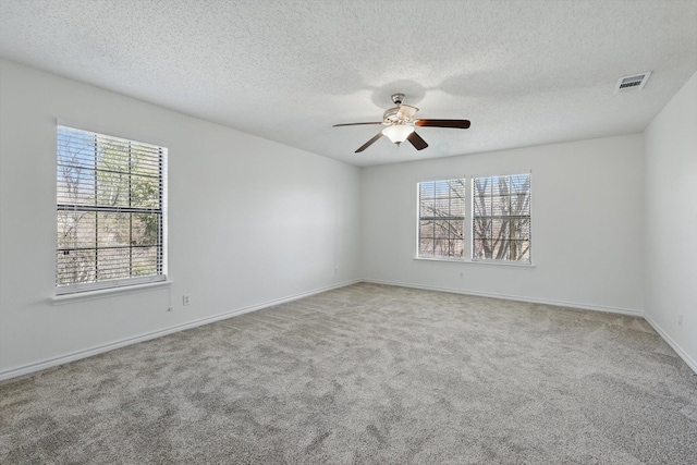 spare room with baseboards, visible vents, carpet floors, ceiling fan, and a textured ceiling