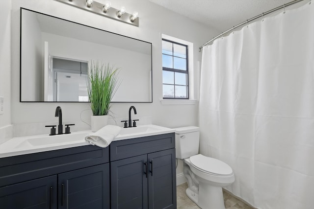 full bath with double vanity, a textured ceiling, toilet, and a sink