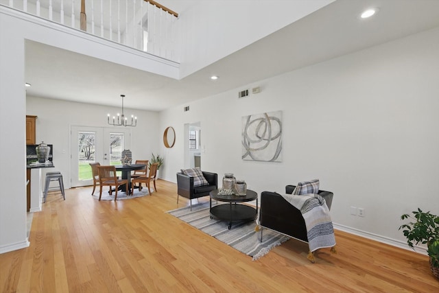 living room with a notable chandelier, recessed lighting, french doors, light wood finished floors, and baseboards