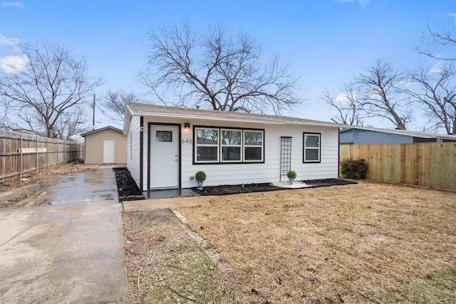 view of front facade with an outbuilding, a storage shed, a front yard, and fence private yard