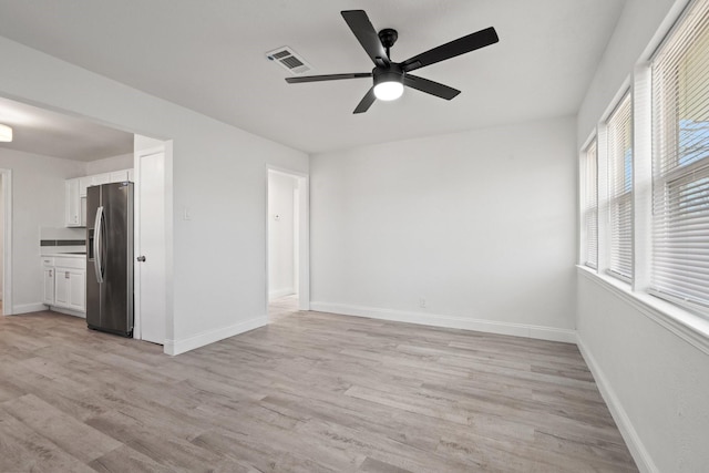 spare room featuring a ceiling fan, baseboards, visible vents, and light wood finished floors