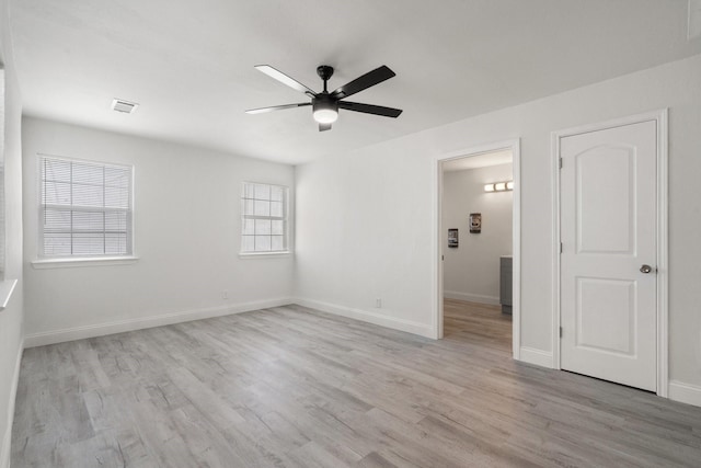 empty room with baseboards, a ceiling fan, visible vents, and light wood-style floors