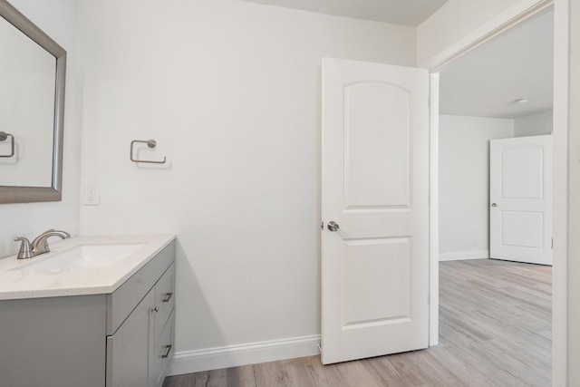 bathroom with baseboards, wood finished floors, and vanity