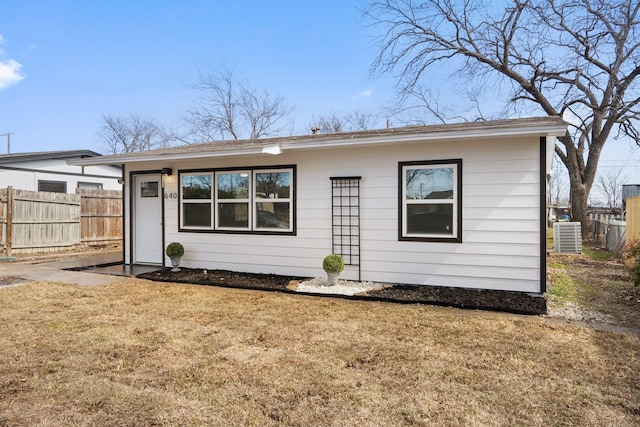 back of property with central AC, fence, and a lawn