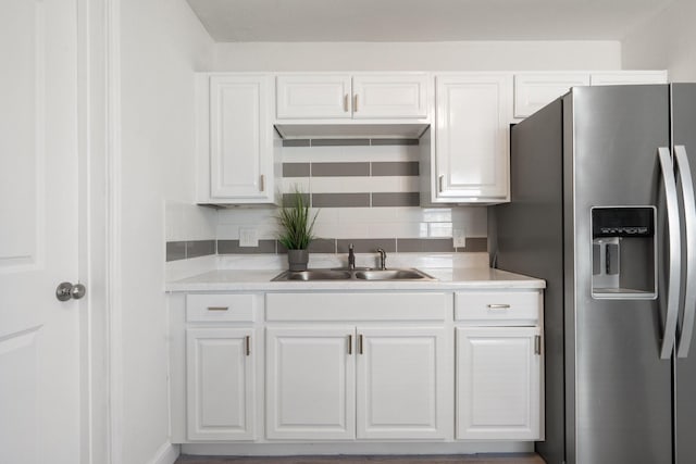 kitchen featuring light countertops, a sink, stainless steel fridge with ice dispenser, and white cabinetry