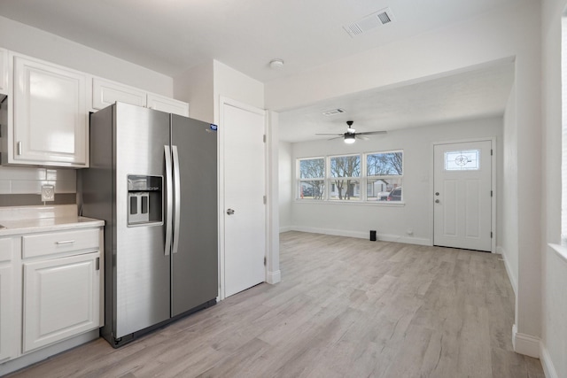 kitchen with visible vents, white cabinets, light countertops, stainless steel fridge with ice dispenser, and light wood finished floors